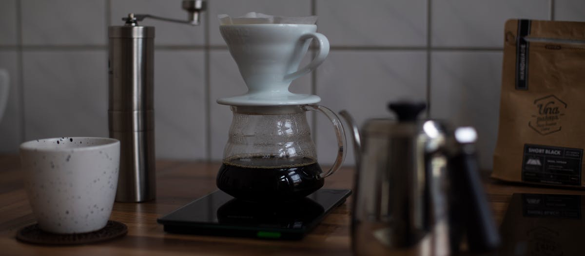 Explore a cozy coffee brewing setup with dripper and ceramic cup on a wooden surface.